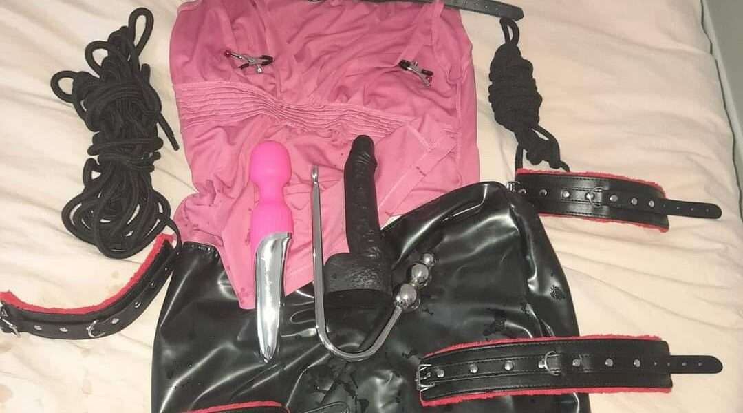 un collier bithc, un haut rose décolleté, cordes, entraves, Wand, gode noir et jupe en simili cuir.